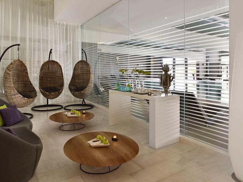 Modern hotel lounge area with hanging chairs, seating, and decorative elements.