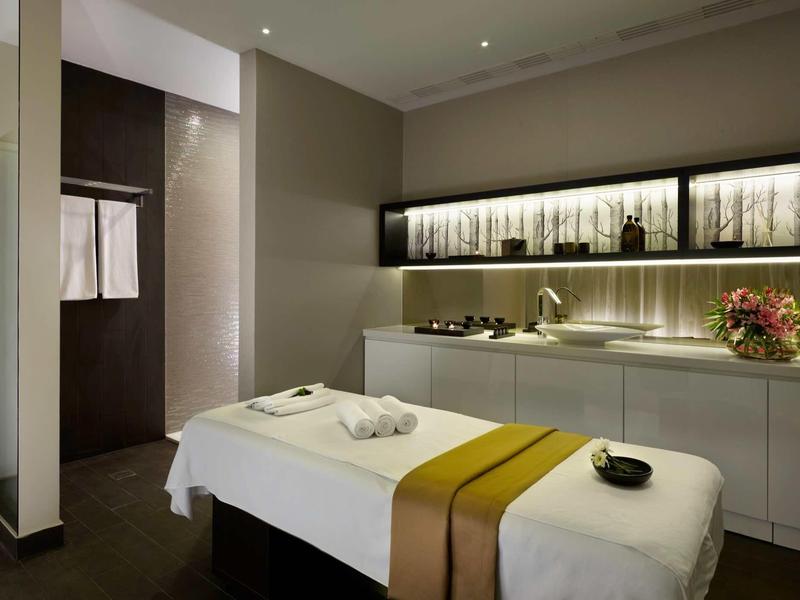 Modern treatment room with massage table in soothing colors and cabinet with decoration.