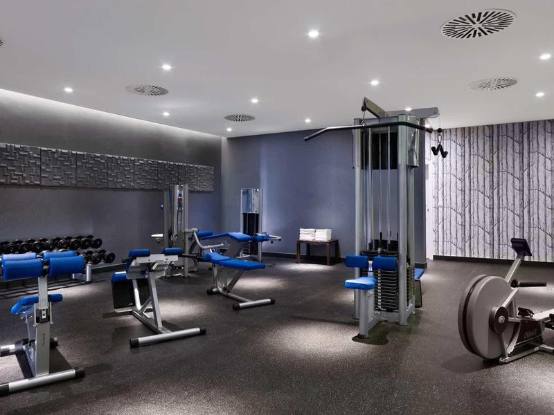 Modern gym with various exercise equipment and subdued lighting.