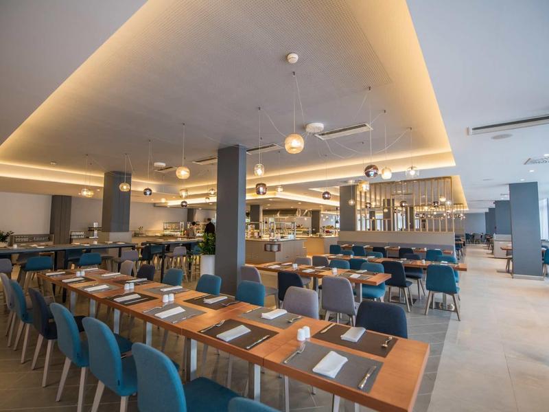 Moderní hotelový bar a restaurace se stylovým nábytkem a teplým osvětlením.