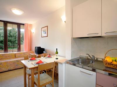 Piccola cucina luminosa con zona pranzo e divano vicino alla finestra a tutta altezza.