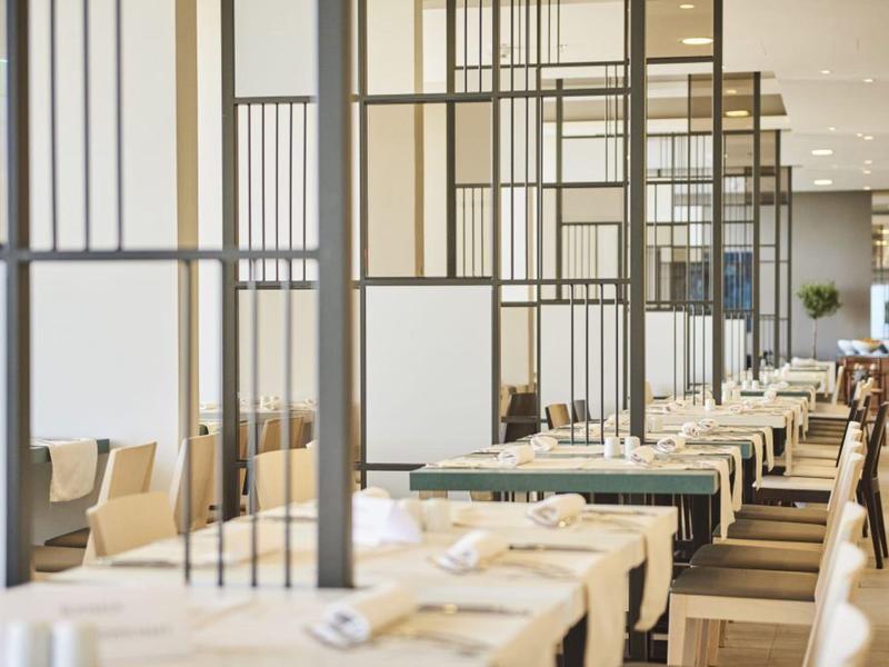 Moderner Restaurantbereich mit elegant gedeckten Tischen und Trennwänden aus schwarzem Metallrahmen.