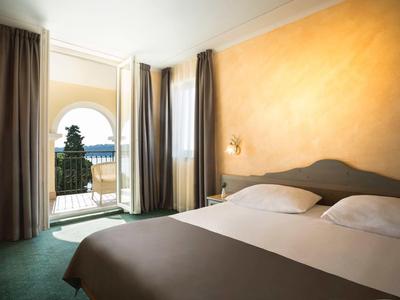 Chambre avec lit double et vue sur la mer par une arche ouverte.