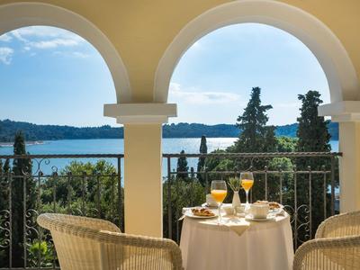 Terraza con mesa puesta con vistas al lago y colinas boscosas bajo cielo despejado.