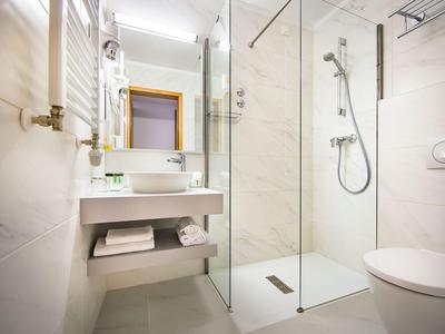Baño moderno de hotel con ducha, inodoro y lavabo con toallas.