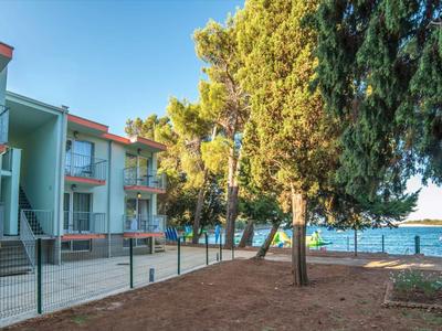 Complexe hôtelier moderne près d'un lac avec ciel bleu clair et arbres.