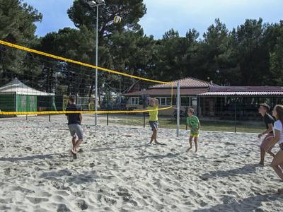 Des personnes jouent au volley-ball sur un terrain de sable en plein air dans un hôtel.