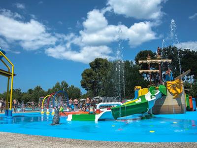 Kolorowy plac zabaw wodnych z zjeżdżalniami i fontannami pod niebieskim niebem w hotelu.