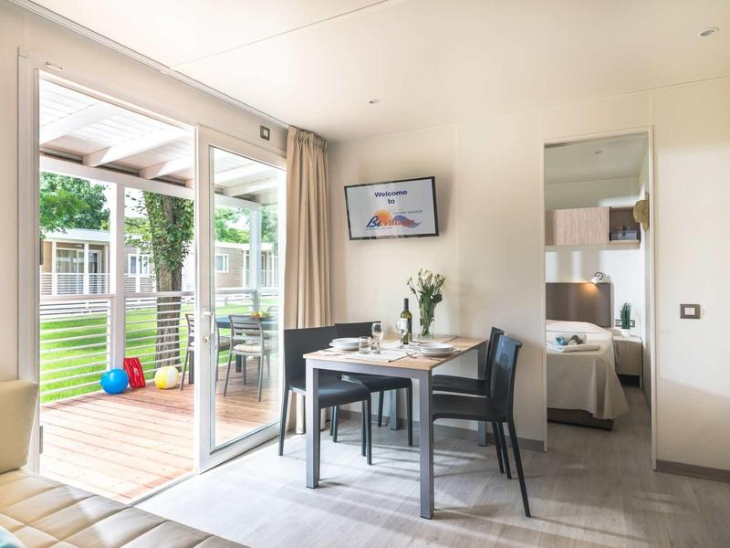 Nowoczesna jadalnia z stołem, krzesłami i widokiem na taras i ogród.