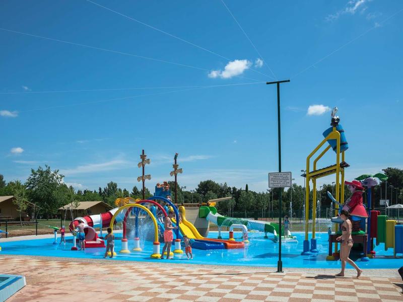 Zjeżdżalnie i plac zabaw w słonecznym basenie dla dzieci pod niebieskim niebem.