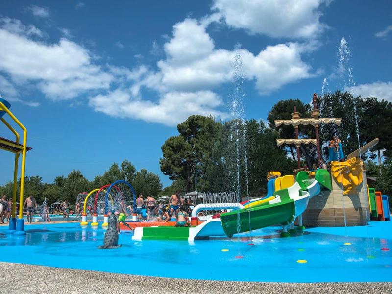 Kolorowy plac zabaw wodnych z zjeżdżalniami i fontannami pod niebieskim niebem w hotelu.