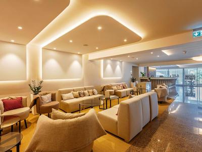 Eleganter Hotellobbybereich mit komfortablen Sofas, modernen Deckenleuchten und großen Fenstern.