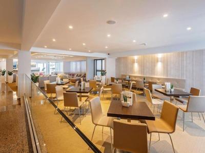 Moderner Speisesaal mit Holztischen und Beistühlen in einem hellen Hotelambiente.