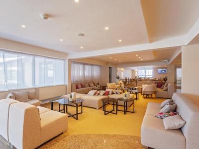 Helles Hotel-Lounge mit modernen Sofas, Couchtischen und großen Fenstern für viel Tageslicht.