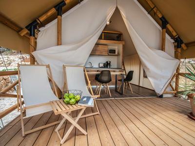 Pohodlná terasa s dřevěnou židlí, malým stolem a moderním stanem s psacím stolem uvnitř.