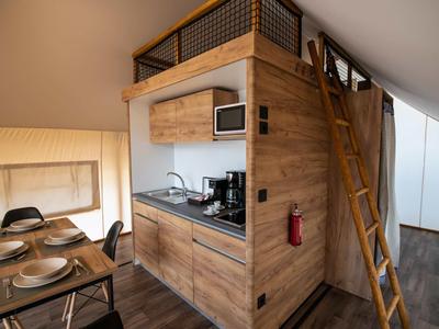 Malá kuchyň s dřevěným obložením a jídelním koutem v moderním apartmánu.