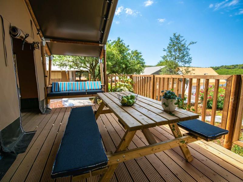 Przytulny drewniany taras z stołem, ławkami i hamakiem na tle wiejskiego krajobrazu.