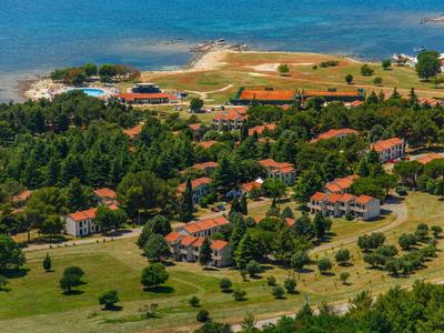 Widok z lotu ptaka na nadmorski hotel z wieloma budynkami i drzewami nad morzem.