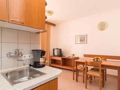 Mała kuchnia z zlewem, ekspresem do kawy i przylegającym miejscem do jedzenia z stołem i krzesłami.