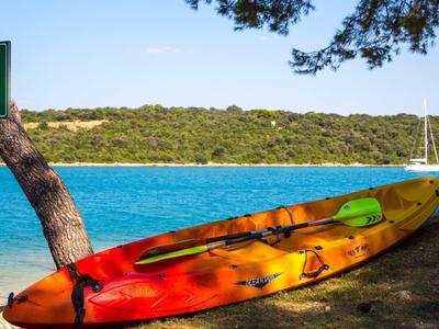 Kayaks colorés au bord d'un lac turquoise avec un paysage boisé en arrière-plan.