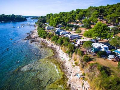 Littoral avec eau claire et camping-cars sur un camping vallonné en bord de mer