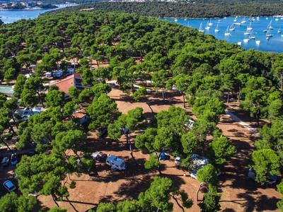 Vue aérienne d'un camping boisé avec des caravanes et des bateaux sur l'eau
