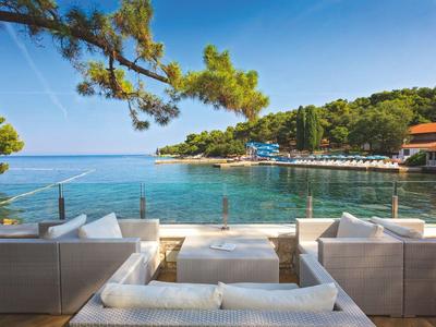 Moderne lounge met uitzicht op een baai met helder water en beboste heuvels.