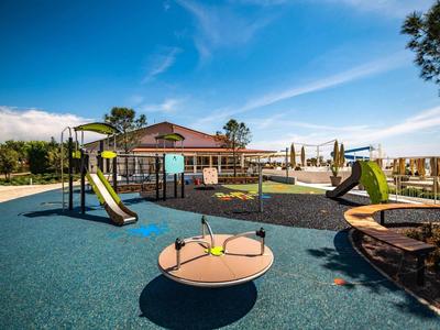 Plac zabaw z zjeżdżalniami, ściankami wspinaczkowymi i karuzelą pod czystym niebieskim niebem.