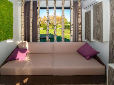 Przytulna beżowa sofa z fioletowymi poduszkami w nowoczesnym pokoju z dekoracją natury.