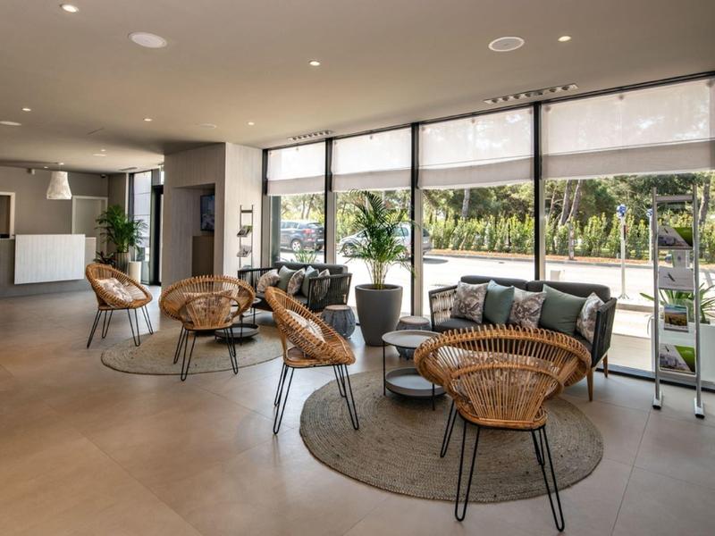 Nowoczesna lobby hotelowa z miejscem do siedzenia, dużymi oknami i elegancką recepcją.