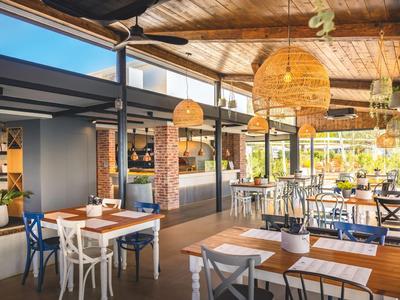 Hell beleuchteter Hotel-Restaurantbereich mit Holztischen und geflochtenen Lampenschirmen