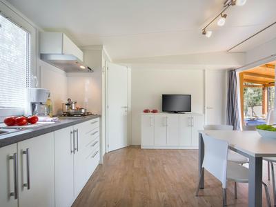 Moderner Küchen- und Essbereich mit weißer Ausstattung, Holzboden und natürlichem Licht.