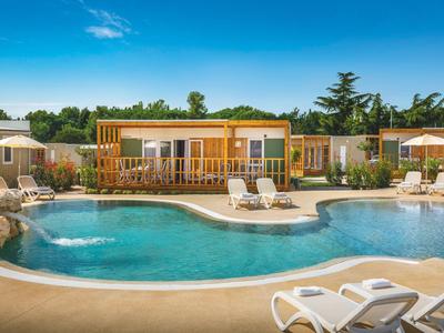 Poolbereich mit Liegestühlen und modernen Bungalows bei sonnigem Wetter