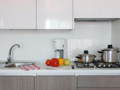 Moderne Küchenzeile mit Spüle, Herd, Kaffeemaschine und frischem Obst auf der Arbeitsplatte.