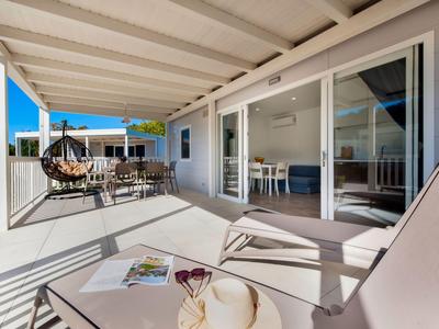 Terrasse mit Sonnenliegen, Esstisch und modernen Glas-Schiebetüren an Hotelzimmer