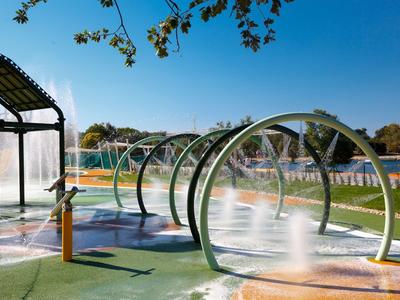 Wasserpark mit mehreren runden Warmwasser-Whirlpools unter klarem Himmel in einem Hotelresort.