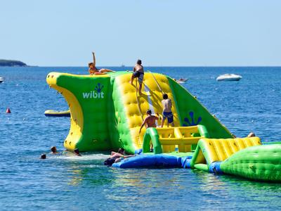 Aufblasbares Wasserhindernis im Meer mit Menschen, die klettern und schwimmen.