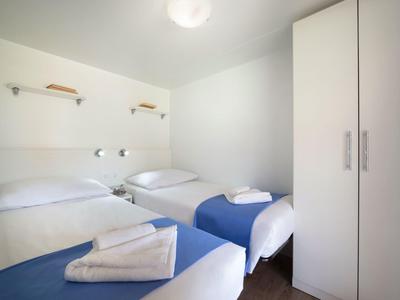 Ein schlichtes Hotelzimmer mit zwei Einzelbetten, weißen Wänden und einem weißen Schrank.