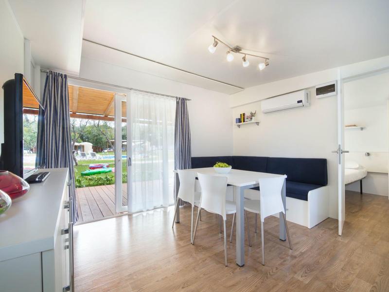 Lichte eetruimte met wit meubilair en uitzicht op terras en tuin.