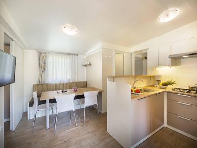 Cocina moderna con comedor abierto y tres sillas blancas en un apartamento vacacional.
