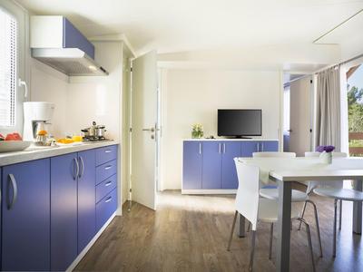 Área moderna de cocina y comedor con gabinetes azules y ventana grande con vista al exterior.