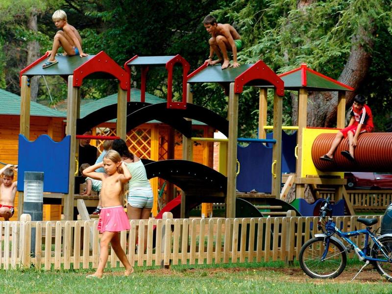 Niños jugando en un parque con estructura de juegos y tobogán en un día soleado