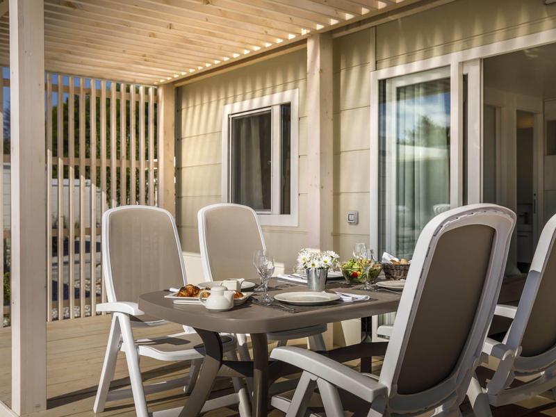 Terraza con mesa y sillas frente a un edificio moderno, soleada y acogedora.