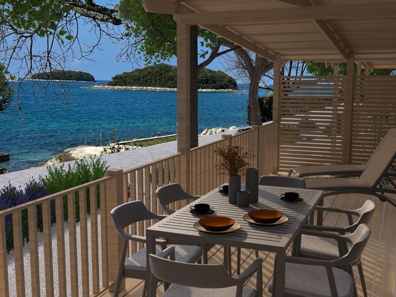 Terraza cubierta con mesa y sillas con vistas al mar y la costa.