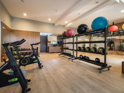 Gimnasio moderno con bicicletas estáticas y pesas sobre suelo de madera.