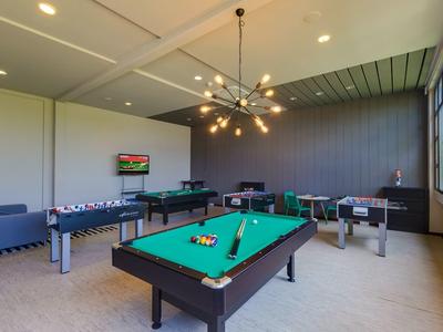 Speelruimte met pooltafel, tafelvoetbal, dartbord en banken in lichte kamer met raam