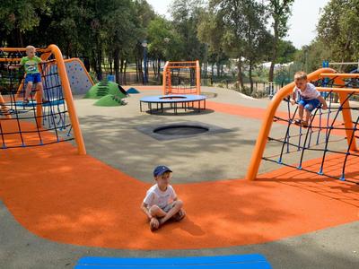 Meerdere kinderen spelen op een moderne speeltuin met klimrekken en trampolines.