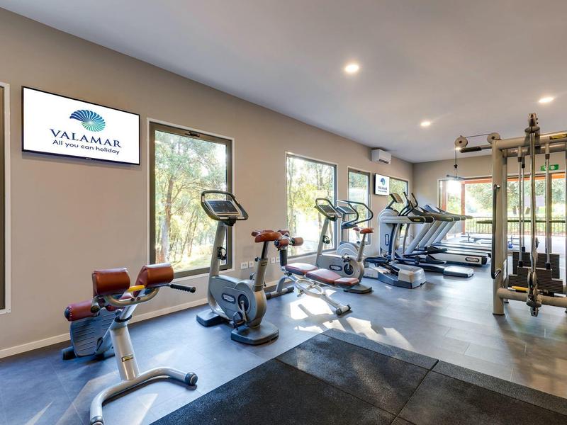 Moderne fitnessruimte met trainingsapparatuur en natuurlijk licht in een hotel.