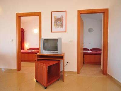 Jednoduchý hotelový pokoj se dvěma ložnicemi, televizí a světlými stěnami.