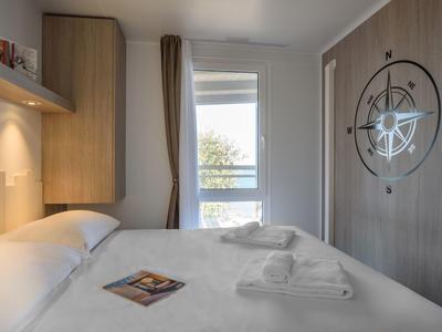 Habitación de hotel acogedora con cama grande, diseño de brújula náutica en la pared y luz natural.